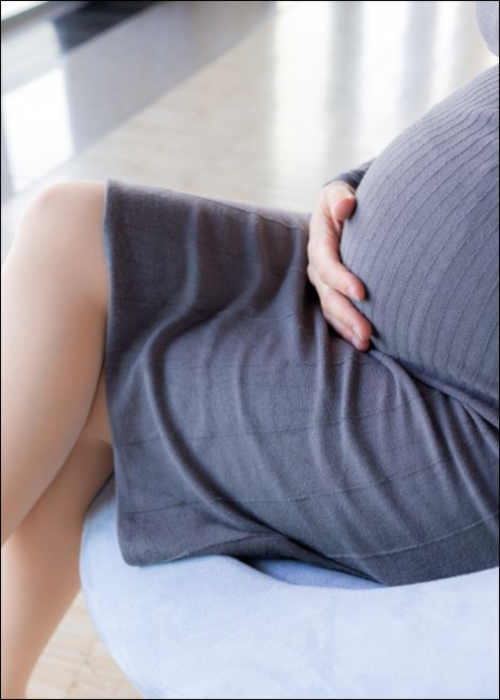 Schwangere Frau sitzt am Flughafen